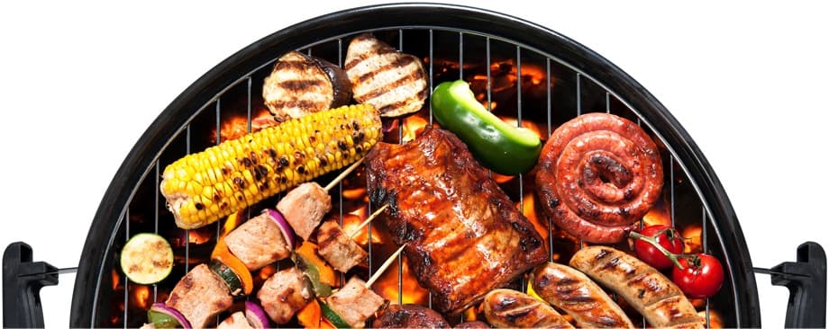 A birdseye photo of a charcoal grill with an assortment of barbecued meats and vegetables.