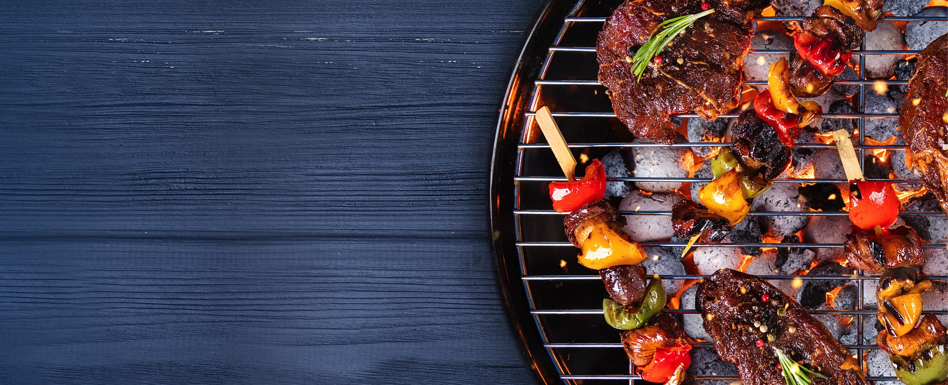A photo of a charcoal grill with an assortment of meat and vegetable skewers.